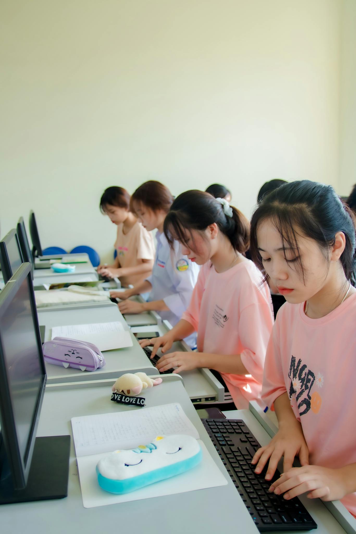 Group of Asian female students learning in a computer classroom.